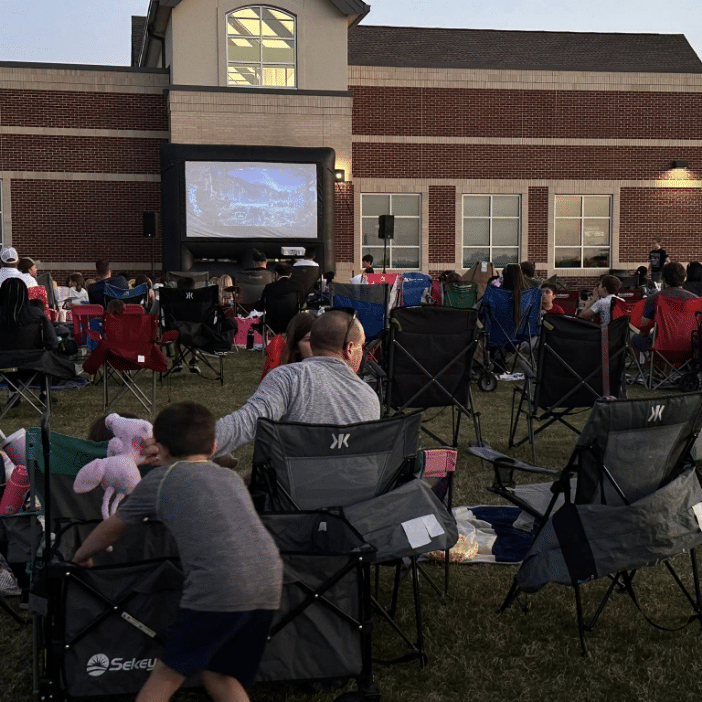 Community watching a movie on a grassy field